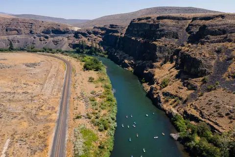 Aerial view of a river running through a canyon with a railroad track alongside.