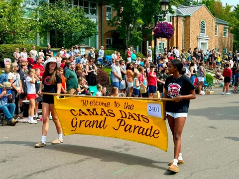 Two people carry a yellow banner at a street parade.