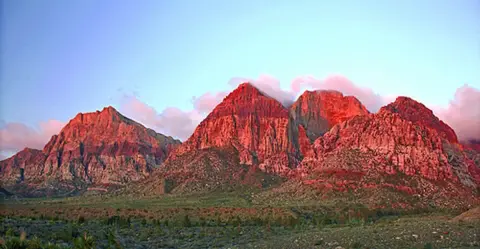 A scenic view of red mountains under a clear sky.