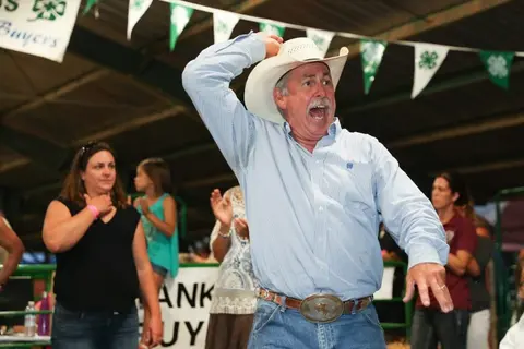 A man in a cowboy hat cheering at an event.