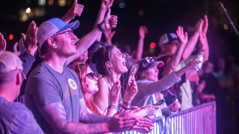 A crowd of people cheering and clapping at an event.