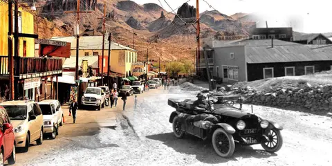 A composite image blending a historic black and white photo of a vintage car on a dirt street with a modern color view of a desert town.