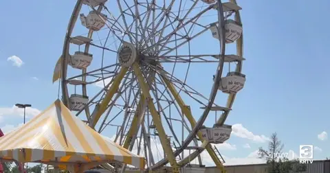 A ferris wheel and carnival tent against a blue sky.