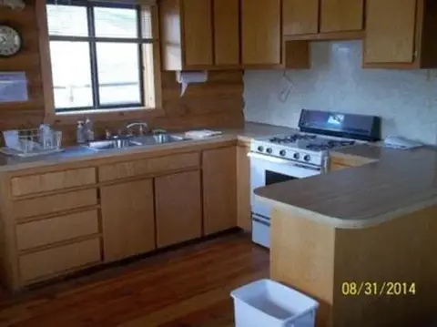 A rustic kitchen with wooden cabinets and a stove.