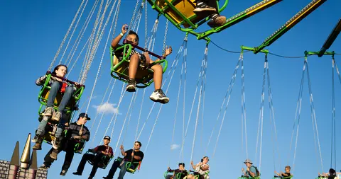 People enjoy riding a swing ride against a blue sky.