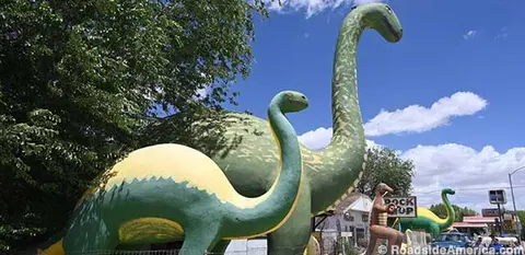 Large dinosaur statues stand outside against a blue sky.