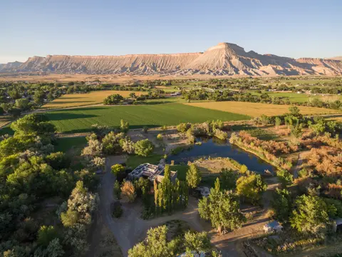 Aerial view of a landscape with a large mountain range, fields, and a pond.