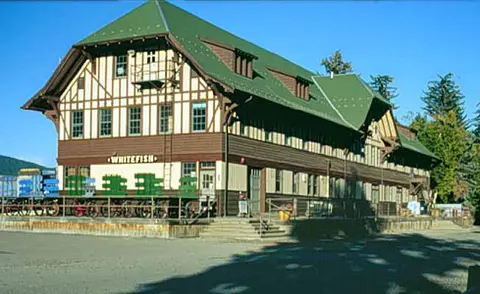 An exterior view of a large historic wooden building with a green roof.