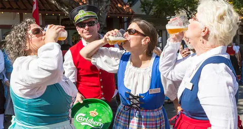 People in traditional-style attire drinking beer outdoors.