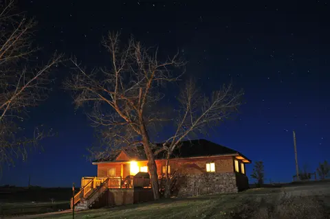 A lit cabin under a starry night sky.