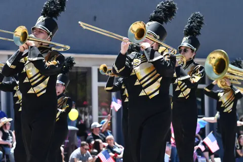 A marching band plays brass instruments in a parade.
