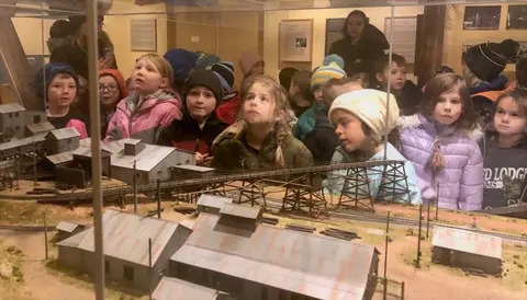 A group of children look at a model exhibit inside a museum.