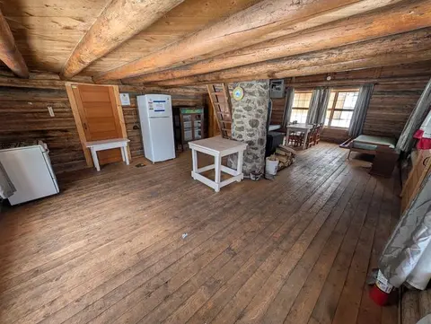 A rustic cabin interior with wooden walls, floors, and ceiling beams.
