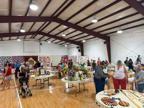 An indoor hall filled with people attending a craft fair or exhibition.