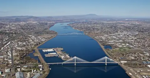An aerial view of a wide river with bridges crossing it and a city surrounding the banks.