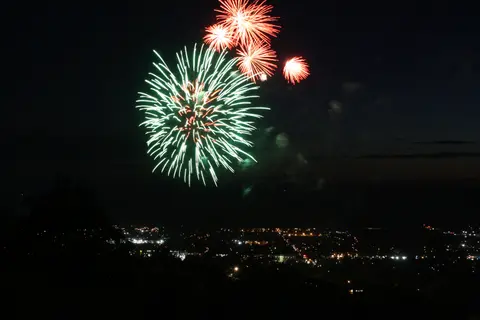 A colorful fireworks display lights up the night sky above a distant city.