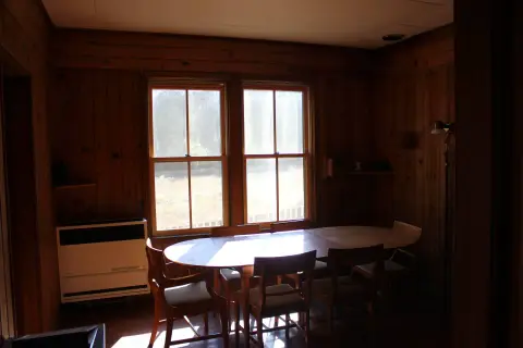 A dining table and chairs inside a wood-paneled room.