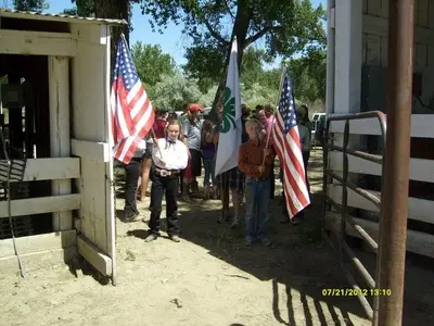 Children holding American flags near farm structures.