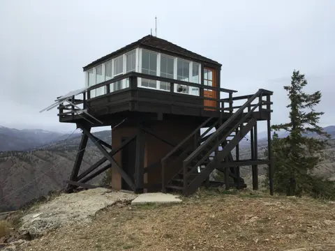 A fire lookout tower stands on a rocky mountain ridge.