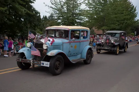 Vintage cars decorated with American flags drive in a parade.