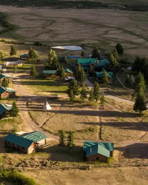 An aerial view of a resort with cabins and green roofs set in a grassy landscape with trees.