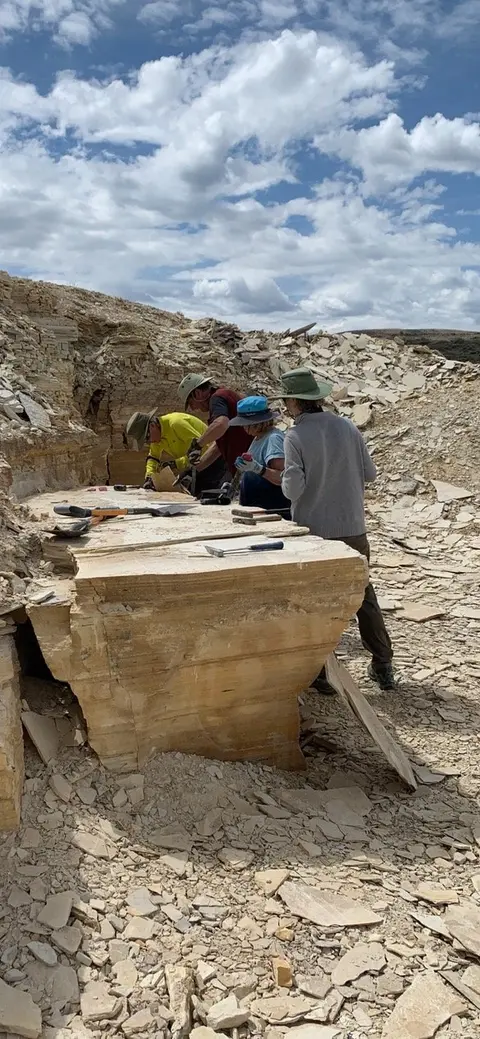 People working at an excavation site in a rocky quarry.