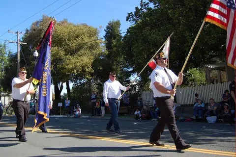 Three people carry flags down a street in a parade.