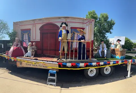 People in historical costumes pose on a parade float.