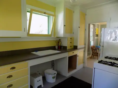 A vintage-style kitchen features yellow cabinets and white walls.