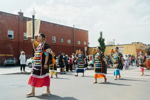 People in traditional attire walking in a street parade.
