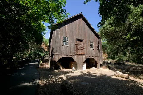 An old wooden building stands surrounded by trees.