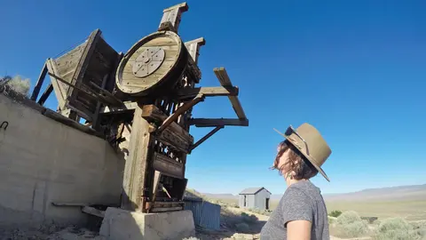 A person looks up at a wooden mining structure outdoors.
