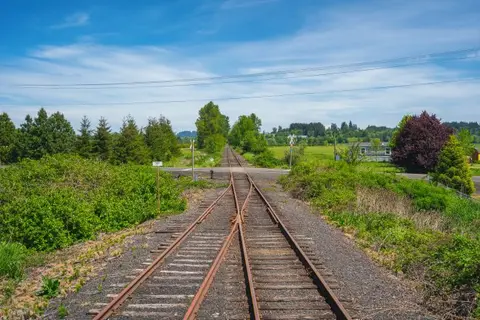 A railroad track stretching into the distance through a rural landscape.