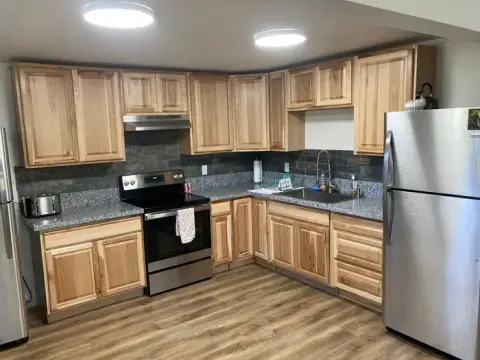 A photo showing the interior of a kitchen with wooden cabinets and stainless steel appliances.