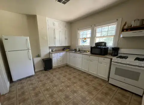 An interior view of a kitchen with white cabinets and appliances.