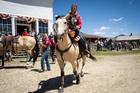 A person rides a horse past a historic building while people watch.